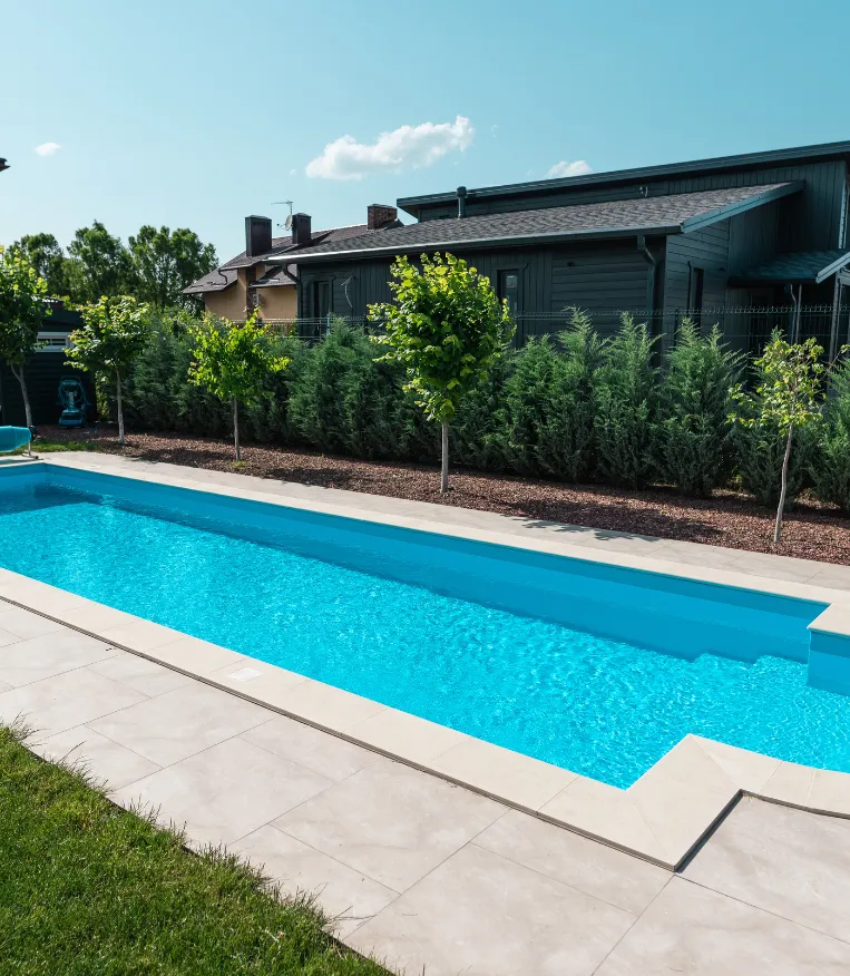 Modern backyard lap pool with clean tile edges and lush landscaping – Dallas Pools Contractor