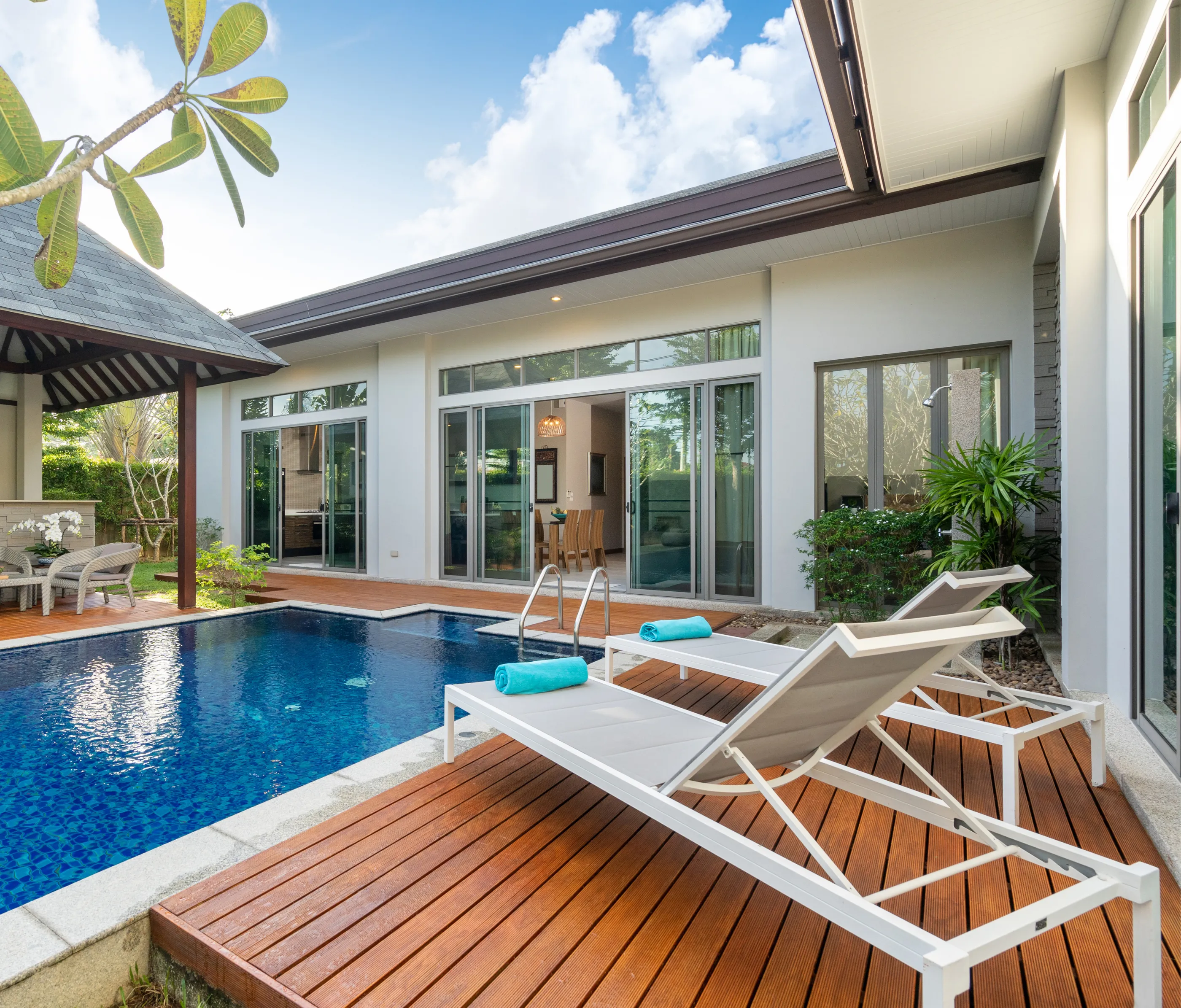 Contemporary pool with wooden deck and lounge chairs near modern glass house – Dallas Pools Contractor