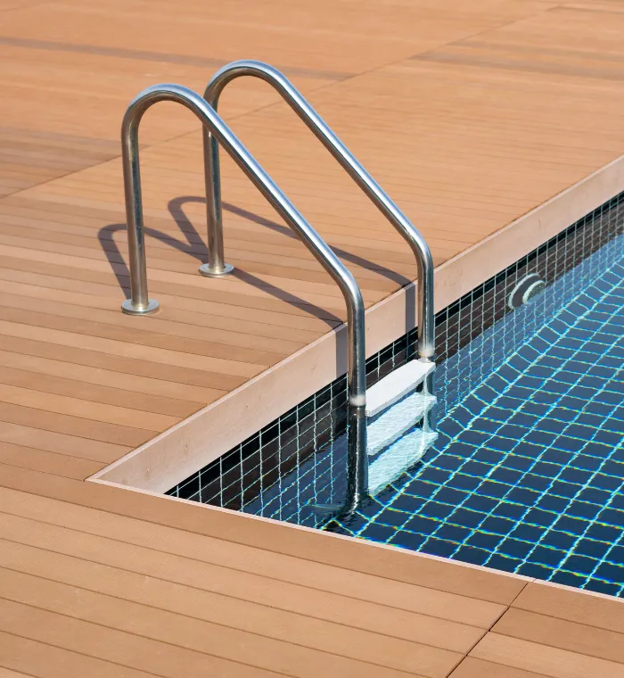 Newly built tiled pool with wooden deck and stainless steel handrail – Dallas Pools Contractor